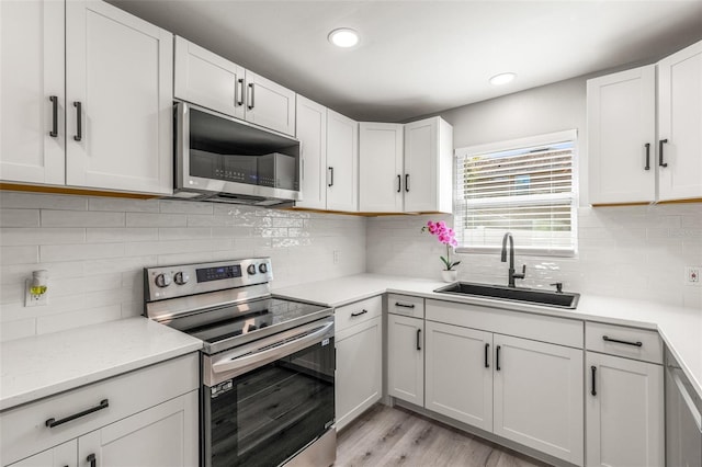 kitchen with appliances with stainless steel finishes, sink, and white cabinets