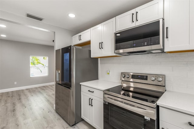 kitchen featuring white cabinetry, decorative backsplash, light hardwood / wood-style floors, and appliances with stainless steel finishes