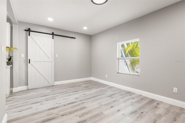 empty room featuring a barn door and light wood-type flooring