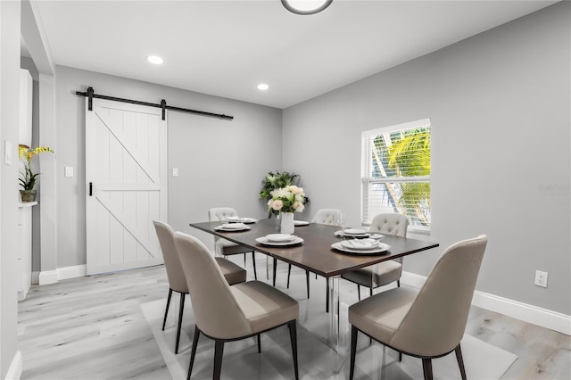 dining room with light hardwood / wood-style floors and a barn door