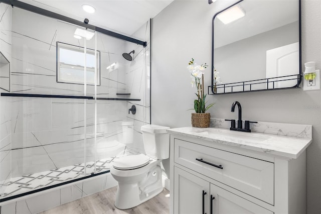 bathroom with wood-type flooring, a shower with shower door, vanity, and toilet