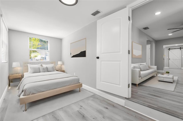 bedroom featuring light hardwood / wood-style floors and a barn door