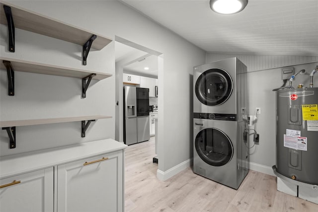 laundry room with water heater, stacked washer and dryer, and light hardwood / wood-style flooring