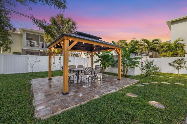 patio terrace at dusk featuring a yard and a gazebo