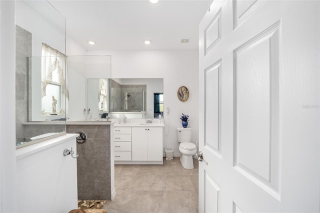 bathroom featuring a tile shower, tile patterned floors, vanity, and toilet