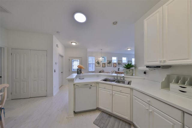 kitchen with decorative light fixtures, kitchen peninsula, sink, white dishwasher, and white cabinets