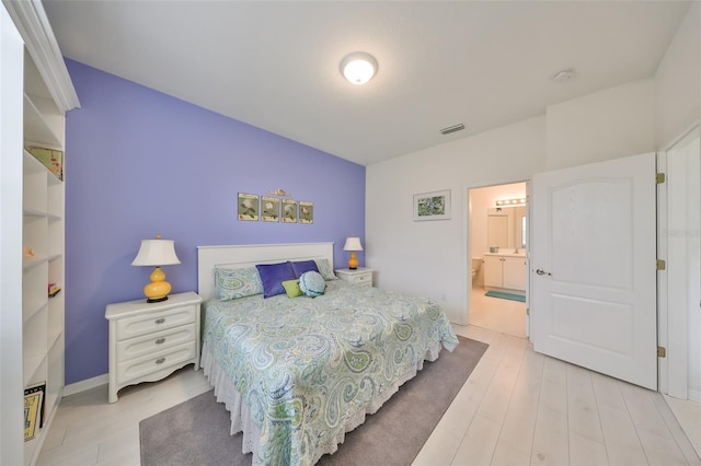 bedroom with ensuite bathroom and light wood-type flooring