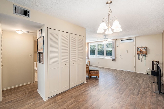 interior space featuring ceiling fan with notable chandelier, dark hardwood / wood-style flooring, and a textured ceiling