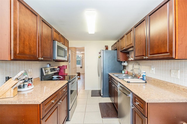 kitchen with light stone countertops, light tile patterned floors, sink, and appliances with stainless steel finishes