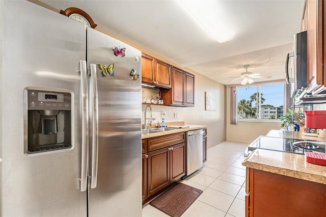 kitchen featuring ceiling fan, sink, stainless steel appliances, decorative backsplash, and light tile patterned floors