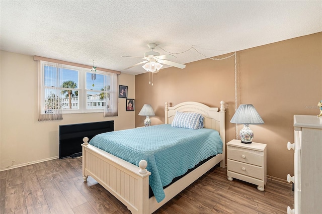 bedroom with ceiling fan, a textured ceiling, and hardwood / wood-style flooring