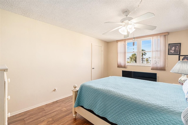 bedroom with ceiling fan, hardwood / wood-style floors, and a textured ceiling