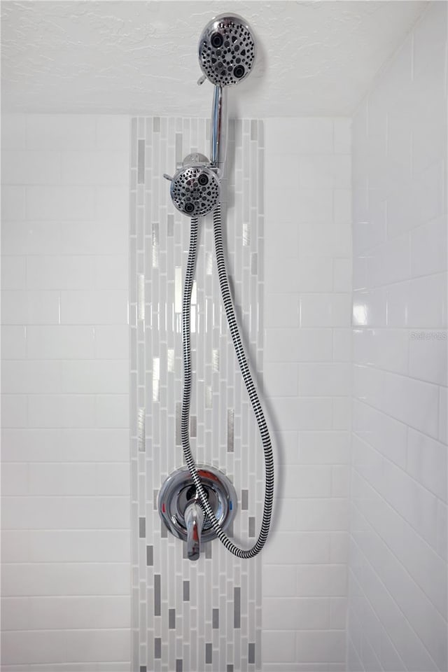 interior details with a tile shower and a textured ceiling