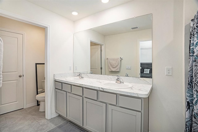 bathroom with toilet, vanity, and tile patterned floors