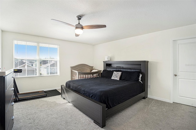 carpeted bedroom featuring ceiling fan and a textured ceiling