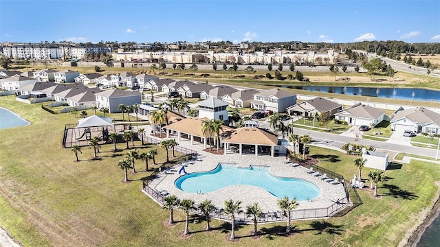 view of swimming pool featuring a water view, a residential view, fence, and a patio