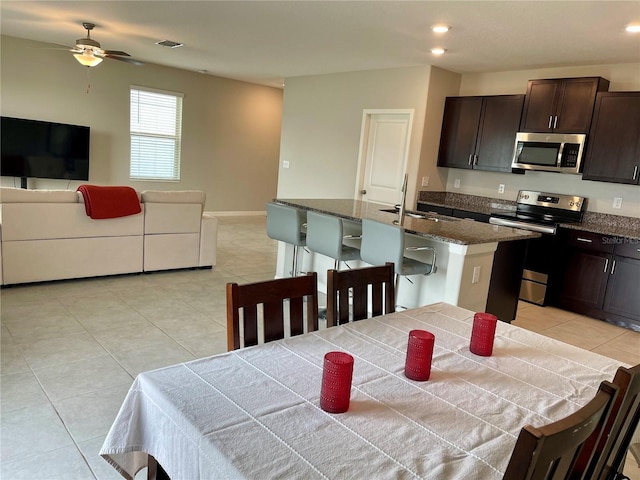 kitchen with sink, dark brown cabinets, a center island with sink, appliances with stainless steel finishes, and ceiling fan