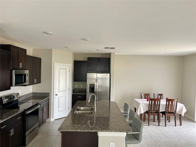 kitchen with appliances with stainless steel finishes, sink, a center island with sink, and light tile patterned floors