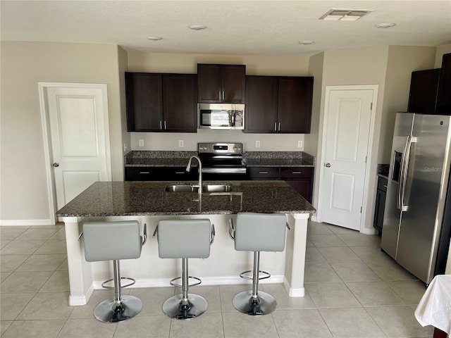 13621 Willow Bluestar Loop, Riverview, FL 33579 - kitchen with appliances with stainless steel finishes, a breakfast bar, dark stone countertops, and light tile patterned floors