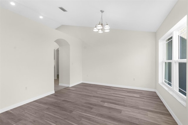 spare room with a chandelier, vaulted ceiling, and dark wood-type flooring