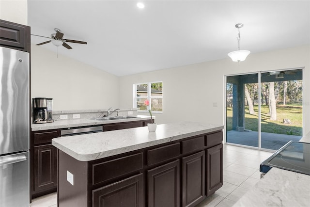 kitchen featuring stainless steel fridge, ceiling fan, sink, decorative light fixtures, and a kitchen island