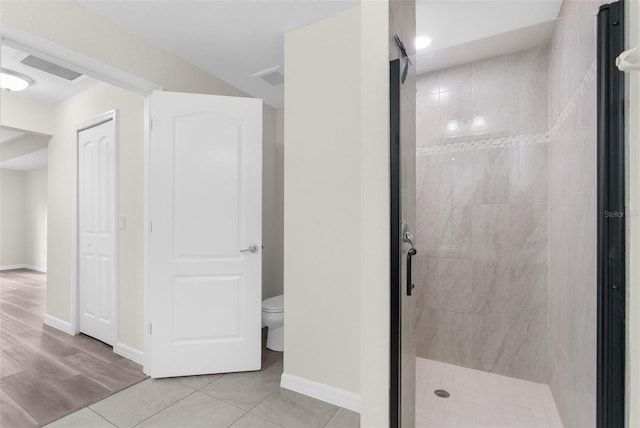 bathroom featuring tile patterned floors, a tile shower, and toilet