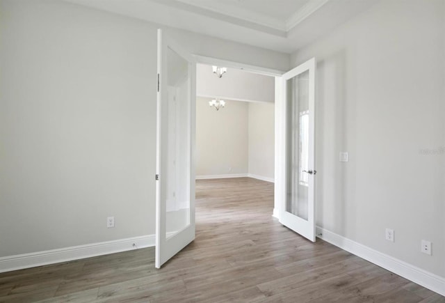 empty room with crown molding, hardwood / wood-style floors, a notable chandelier, and french doors