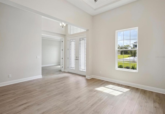 entryway with light hardwood / wood-style floors, french doors, and an inviting chandelier