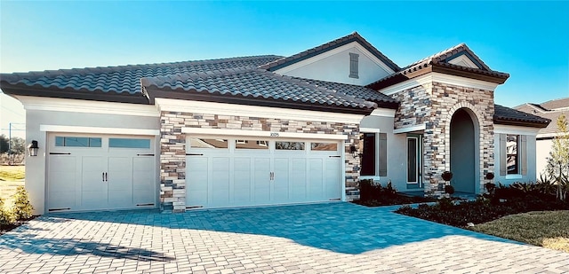 view of front of house featuring a garage, stone siding, a tiled roof, and stucco siding