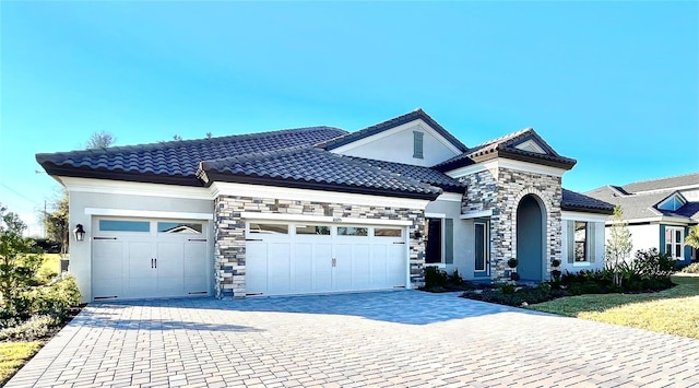 view of front of home featuring a garage, decorative driveway, a tile roof, and stucco siding