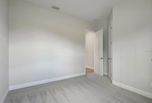 carpeted empty room with visible vents and baseboards