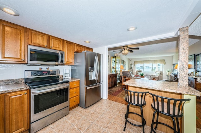 kitchen with a breakfast bar area, stainless steel appliances, and a textured ceiling