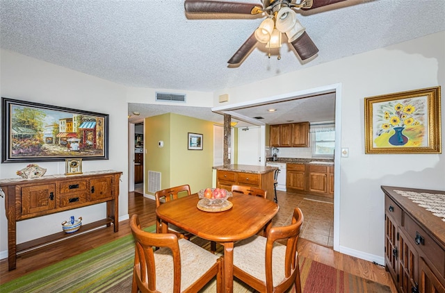 dining space with ceiling fan, a textured ceiling, and hardwood / wood-style flooring