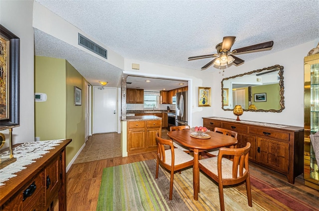 dining area featuring a textured ceiling, ceiling fan, dark hardwood / wood-style flooring, and sink