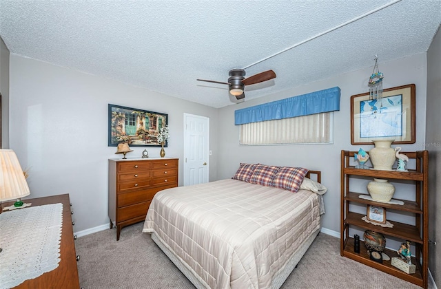 carpeted bedroom with ceiling fan and a textured ceiling