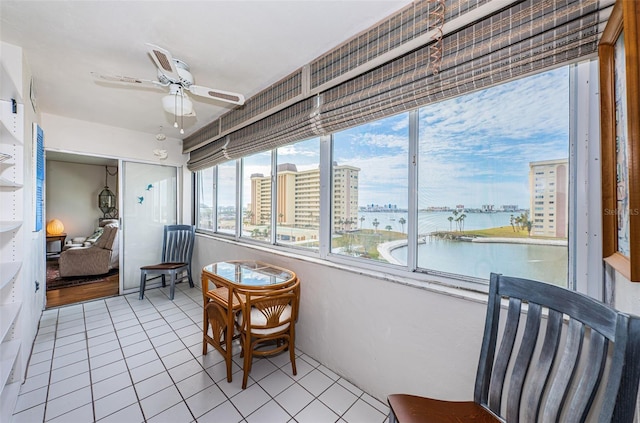 sunroom with ceiling fan and a water view