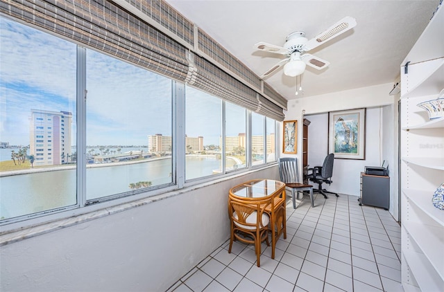 sunroom / solarium featuring ceiling fan and a water view