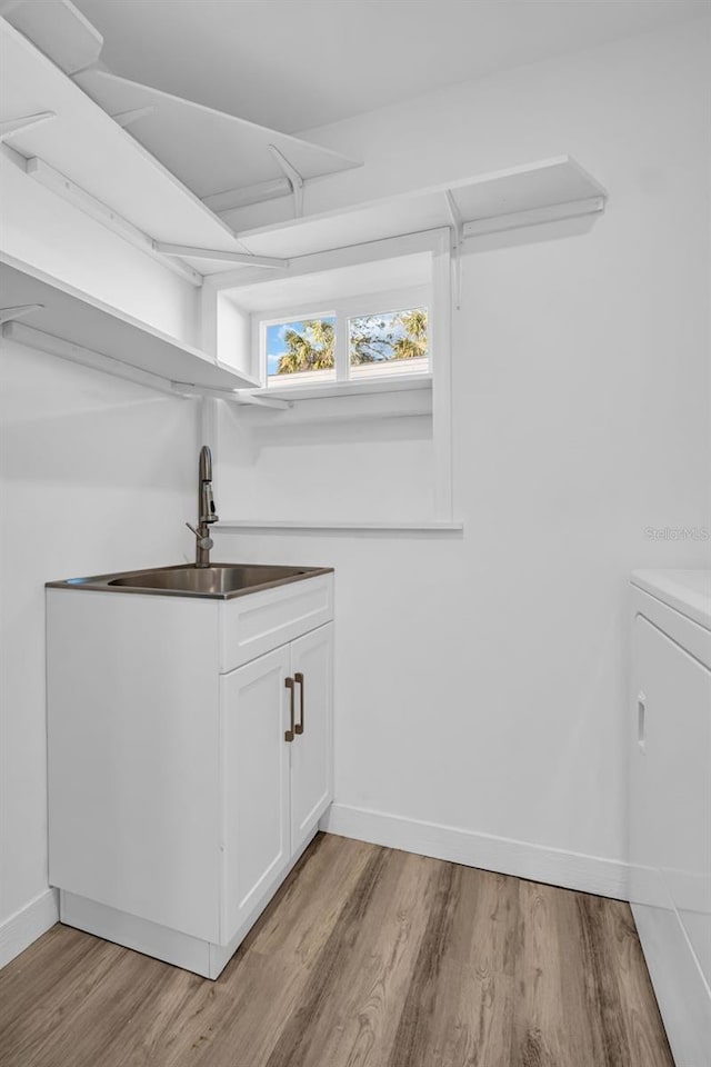 laundry area featuring washer / dryer, sink, and light hardwood / wood-style flooring