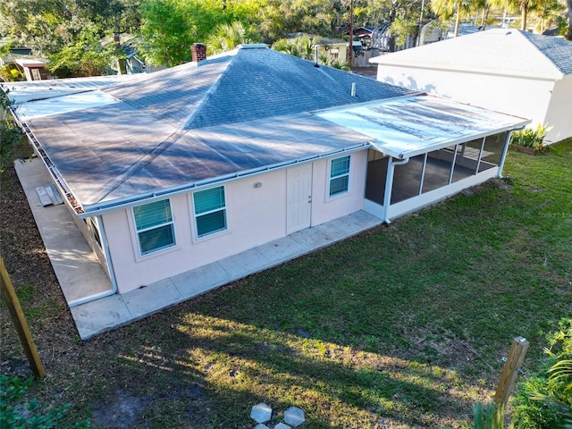 rear view of property featuring a yard and a sunroom