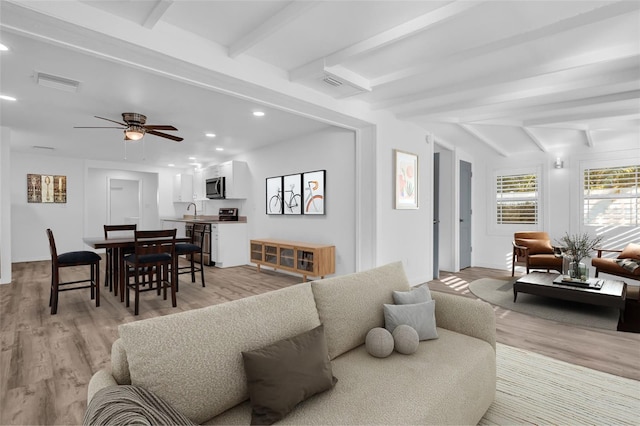 living room with beamed ceiling, ceiling fan, sink, and light hardwood / wood-style flooring