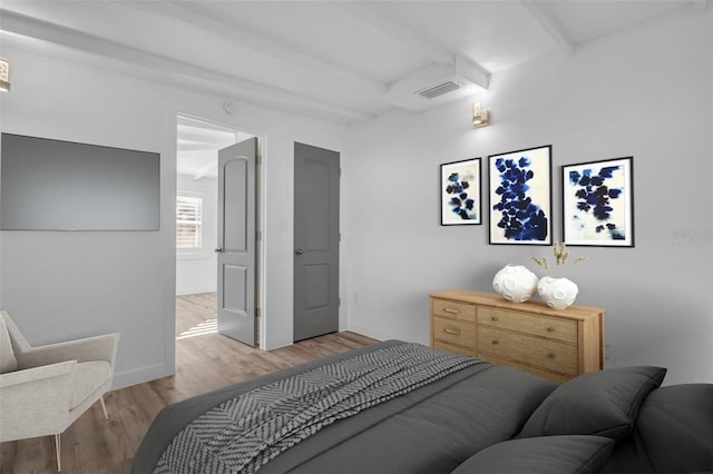 bedroom featuring beamed ceiling and light hardwood / wood-style floors