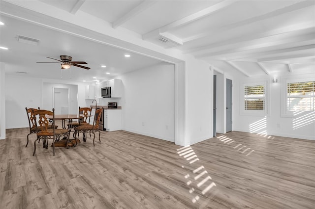 dining space with ceiling fan, beamed ceiling, and light wood-type flooring