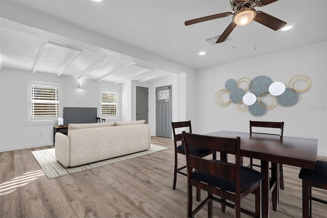 dining space featuring ceiling fan, light hardwood / wood-style flooring, and vaulted ceiling with beams