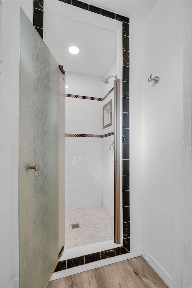 bathroom with hardwood / wood-style floors and a tile shower