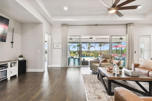5226 Lake Venice Dr, Wimauma, FL 33598 - living area featuring a ceiling fan, a tray ceiling, baseboards, and dark wood-style flooring