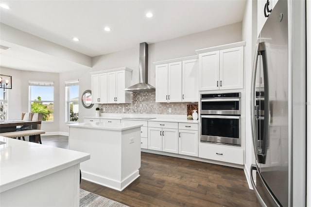 5226 Lake Venice Dr, Wimauma, FL 33598 - kitchen with backsplash, a kitchen island, appliances with stainless steel finishes, white cabinetry, and wall chimney exhaust hood