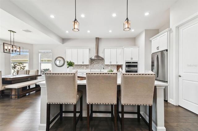5226 Lake Venice Dr, Wimauma, FL 33598 - kitchen with backsplash, wall chimney range hood, an island with sink, appliances with stainless steel finishes, and dark wood-style floors