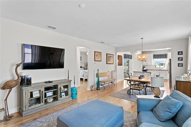 living room with a chandelier and light wood-type flooring