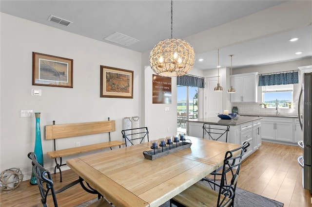 dining area featuring light hardwood / wood-style floors, a notable chandelier, and sink