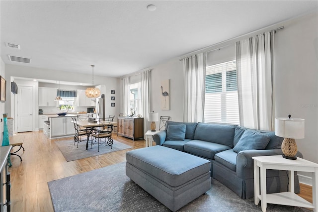 living room featuring plenty of natural light, a notable chandelier, and light hardwood / wood-style flooring